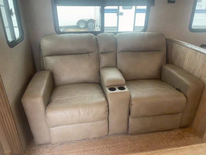 Inside an RV rental: Plush two-seat recliner sofa with center console and cup holders for travel comfort.. Palomino Solaire Ultra Lite 2020