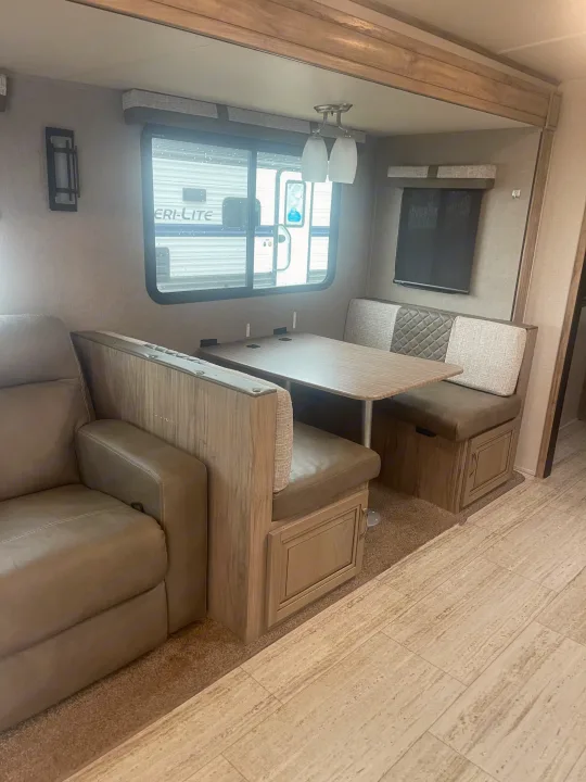 Spacious RV rental interior featuring a comfy couch, dining booth with table, and windows. Perfect for your next adventure.. Palomino Solaire Ultra Lite 2020