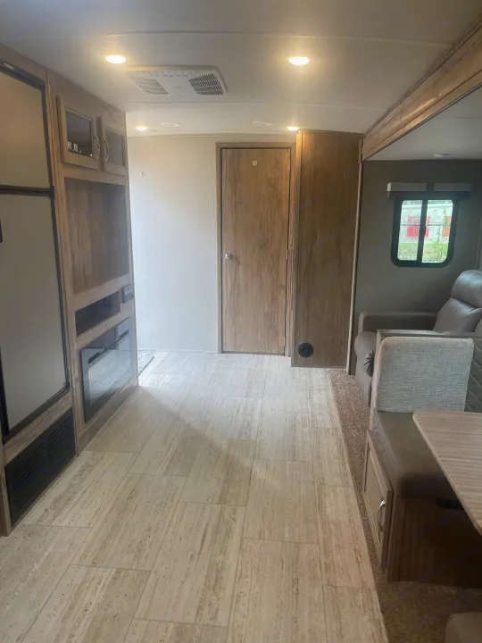 Interior view of an RV rental: light wood-look floor, built-in cabinets, fridge, and dinette with a window. Ready for your trip.. Palomino Solaire Ultra Lite 2020