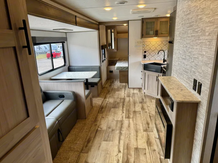 Explore this bright RV rental interior featuring a cozy dinette, modern kitchen with black sink, and warm wood-look finishes.. Coleman Lantern 2022