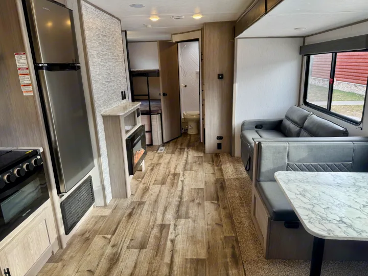 Inside a clean RV rental: kitchen with fridge/stove, cozy dinette, fireplace, plus bunk beds and bathroom access.. Coleman Lantern 2022