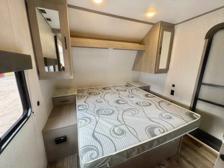 Experience comfort in this RV rental bedroom: features a patterned mattress, nightstands, and overhead storage.. Coleman Lantern 2022