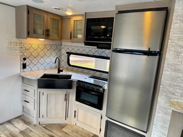This bright, functional RV kitchen, perfect for an rv rental, boasts modern appliances, light wood cabinetry, & a large sink.. Coleman Lantern 2022
