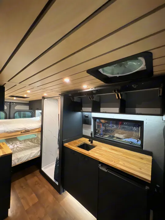 Modern camper van rv rental interior featuring a full kitchen, bunk beds, and shower. Ready for adventure travel.. Dodge Sportsman 2025