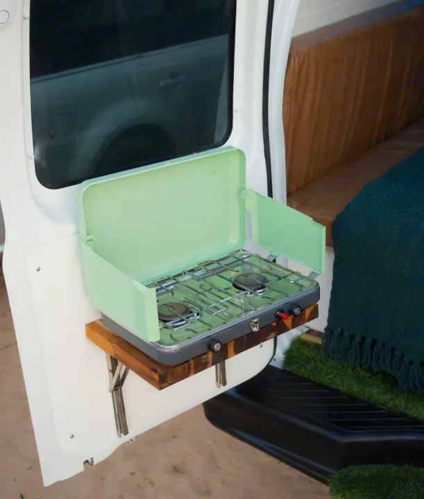 This RV rental features outdoor cooking: a mint green portable camp stove on a clever fold-down wooden shelf.. Ford Econoline 2006