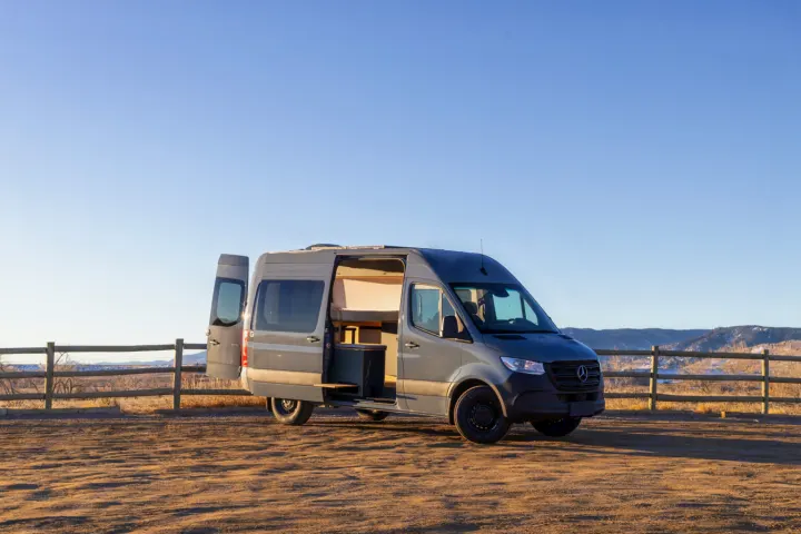 Experience the open road! Gray Sprinter camper van, perfect RV rental, parked with doors open, showcasing custom interior build.. Mercedes-Benz Sprinter 2024