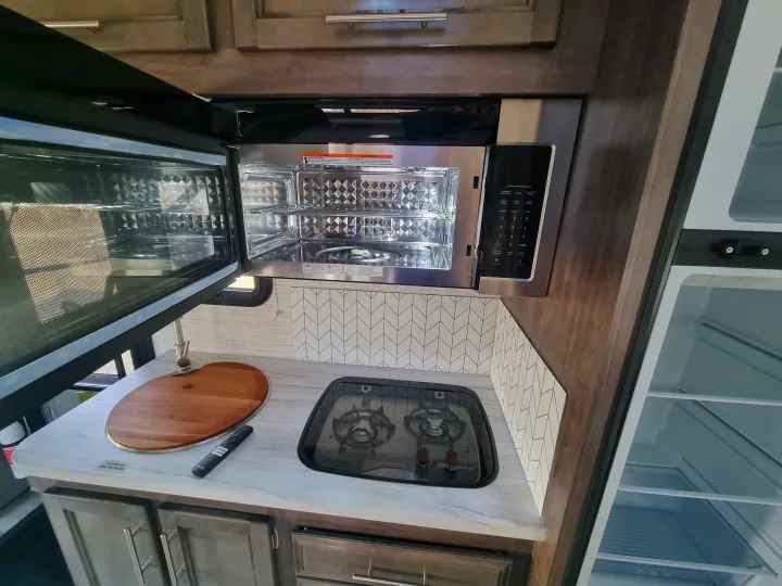 Modern rv rental kitchen with convection microwave, gas stovetop, and refrigerator. Compact and ready for adventure.. Entegra Qwest SE 2025 Qwest 2025 Mercdes-Benz 2025