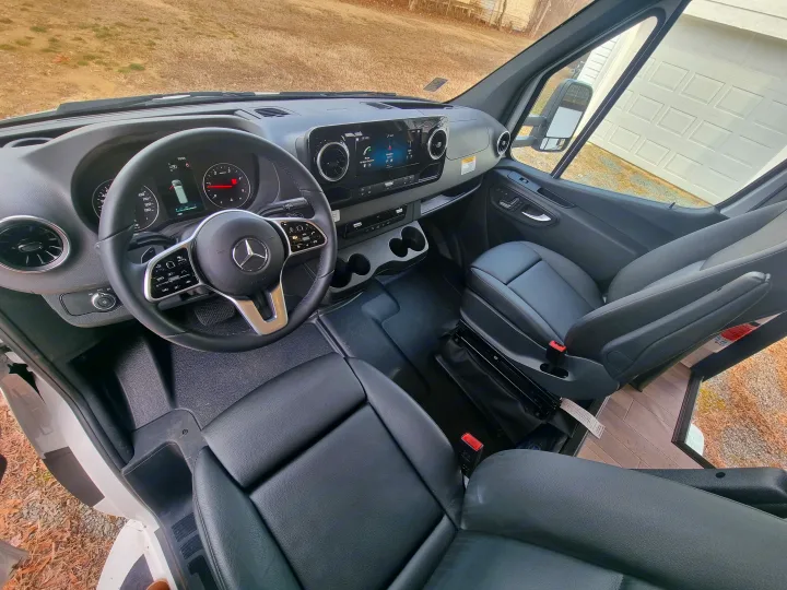 Interior view of a modern RV rental cockpit, featuring a Mercedes-Benz dashboard, infotainment system, and black leather seats.. Entegra Qwest SE 2025 Qwest 2025 Mercdes-Benz 2025