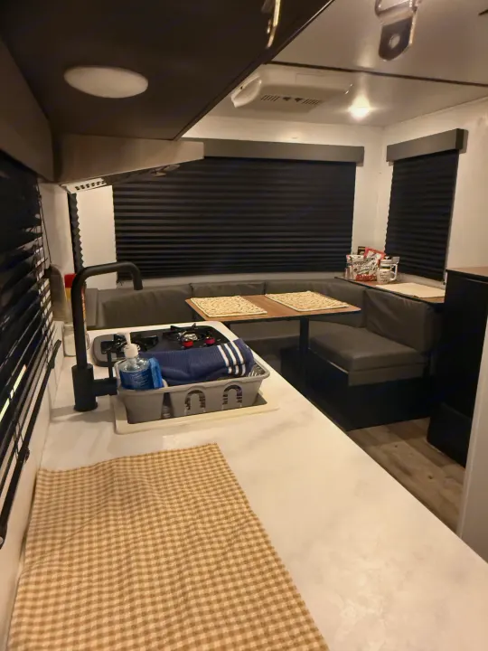 Cozy RV rental interior with a kitchen, stove, sink, dinette, and dark blinds, ready for your next road trip.. Forest River Wildwood FSX 2022