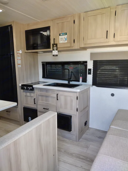Bright rv rental interior featuring a compact kitchenette with modern appliances and a comfortable dinette.. East to West Della Terra LE 2024