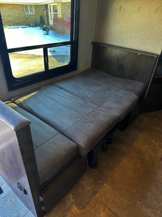 Inside an RV rental: Dinette seating converted to a comfy bed, with a view of a snowy outdoor scene.. Jayco Jay Flight SLX 2020