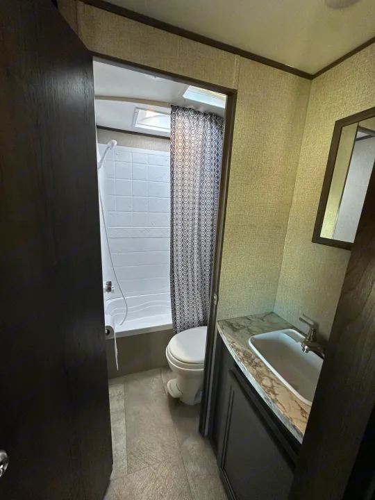 Inside an RV rental: a compact bathroom featuring a shower, toilet, and sink vanity. Ideal for road trips.. Jayco Jay Flight SLX 2020