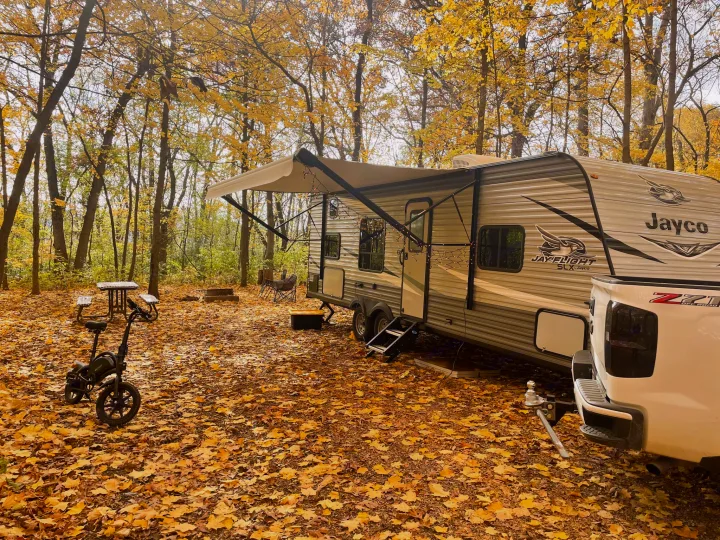 Autumn RV rental camping. A Jayco travel trailer with a white truck, e-bike, & fall leaves at a vibrant campsite.. Jayco Jay Flight SLX 2020