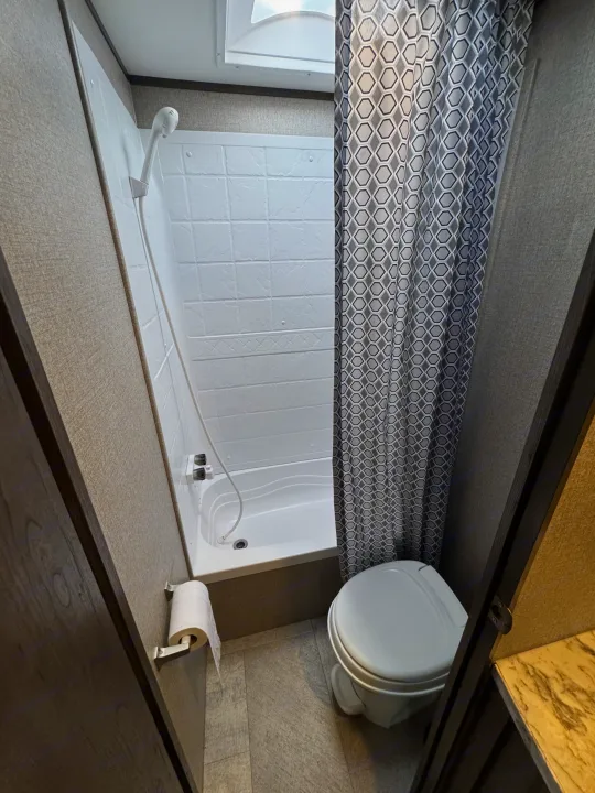 Compact RV rental bathroom featuring a shower/tub combo and toilet, ready for your travel adventures.. Jayco Jay Flight SLX 2020