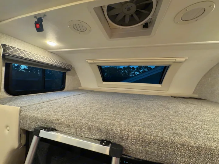 Experience comfort in this RV rental's spacious cab-over sleeping bunk, featuring windows, fan, vent, and access ladder.. Thor Quantum 2022