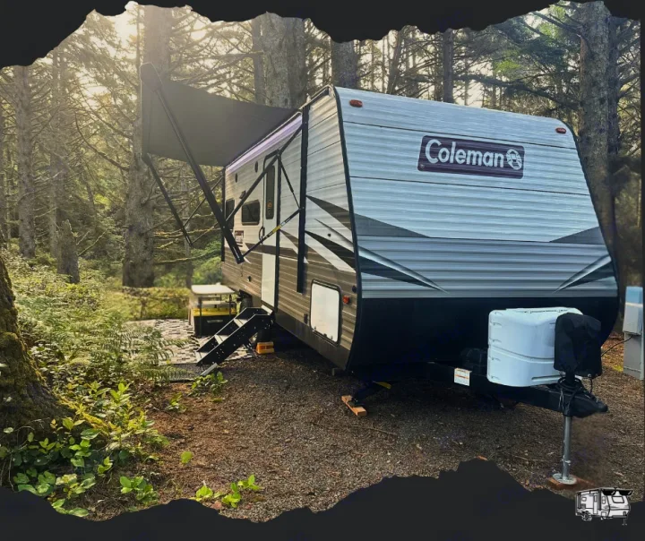 Experience a comfortable RV rental: A Coleman travel trailer parked at a serene forest campsite with awning extended.. Dutchmen Coleman Lantern LT 2021