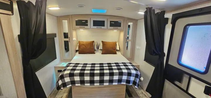 Enjoy a comfortable RV rental bedroom featuring a cozy bed, overhead storage, and privacy curtains.. Heartland RVs Sundance Ultra Lite 2022