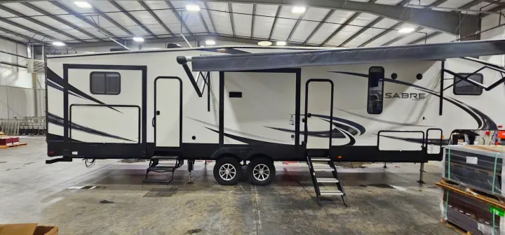 Large Sabre Cobalt RV in a warehouse, ideal for rv rental. Note the extended awning, steps, and sleek graphics.. Forest River Sabre 2019