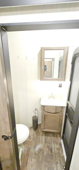 Compact RV rental bathroom features a toilet, vanity with sink, and mirror, perfect for travel comfort.. Forest River Sabre 2019