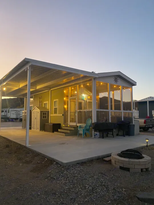 Well-lit RV rental home at an RV park. Enjoy the spacious covered patio, string lights, and fire pit for evening relaxation.. ATHMS CCHPT 2019