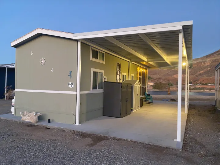 Modern manufactured home with a lit covered patio by water and mountains; ideal for an RV rental escape.. ATHMS CCHPT 2019