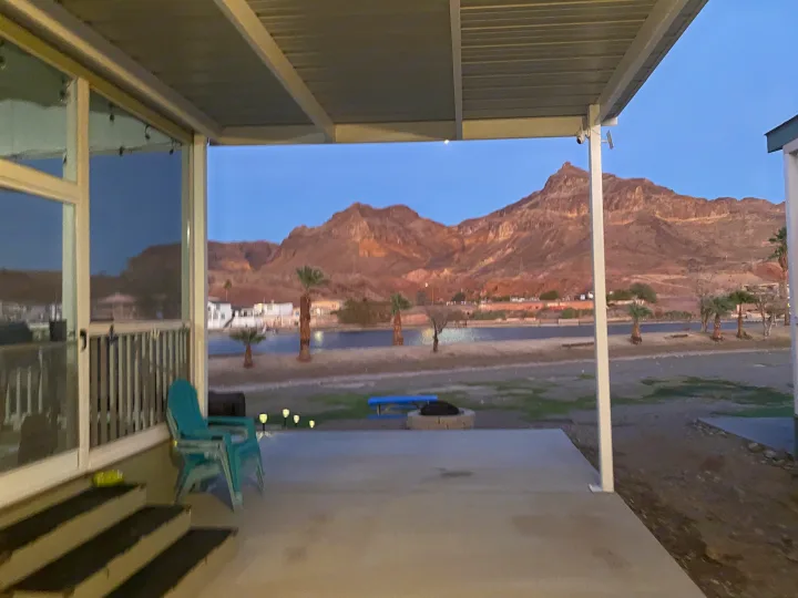Waterfront RV rental patio with serene lake and mountain views at dusk, perfect for a relaxing desert vacation.. ATHMS CCHPT 2019