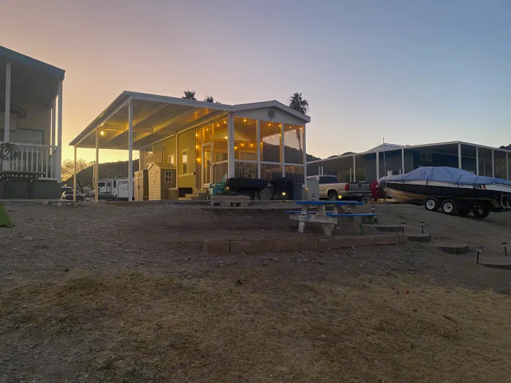 Twilight in a desert RV resort. A cozy RV rental home with a string-lit patio and a boat nearby offers relaxation.. ATHMS CCHPT 2019