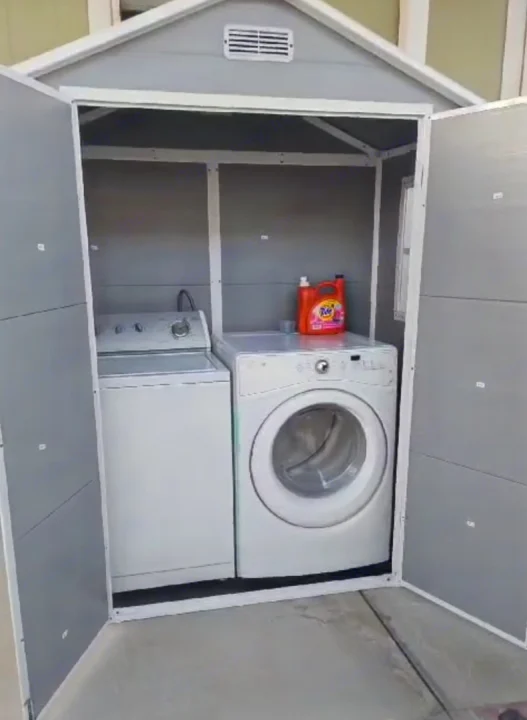 Compact outdoor laundry shed, perfect for an RV rental, houses a white washer, dryer, and laundry detergent.. ATHMS CCHPT 2019