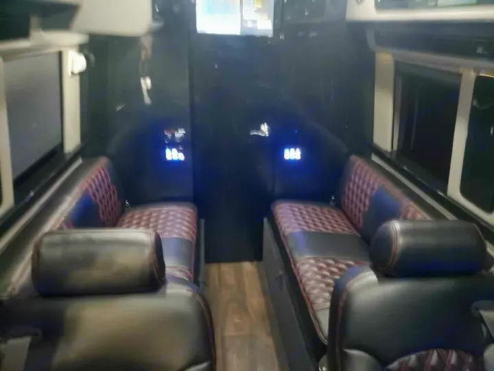 Custom RV rental interior with plush, facing black and red quilted leather seats and blue wall lights.. Midwest Automotive Designs Midwest Automotive Designs Class B 2016
