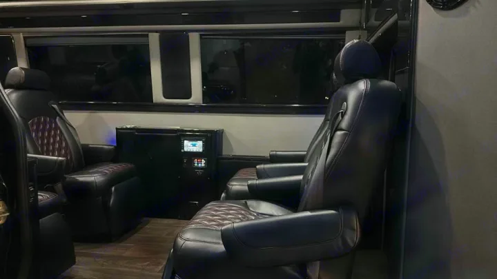 Luxury RV rental interior with plush captain's chairs, modern controls, and dark wood-look floor for comfortable travel.. Midwest Automotive Designs Midwest Automotive Designs Class B 2016