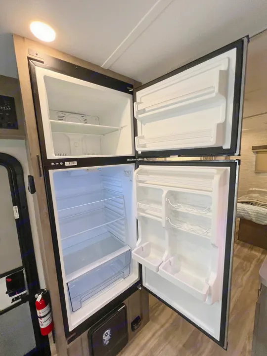 RV rental kitchen amenities: A bright, empty two-door refrigerator and freezer, ready for your provisions.. Gulf Stream Conquest 2025