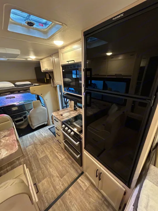 Spacious RV rental interior with full kitchen, overhead bunk, and cozy living area. Ideal for travel adventures.. Thor Motor Coach Chateau 2026