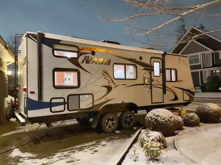 Snowy night view of a white Nash RV rental parked with interior lights on, surrounded by snow-covered ground.. Nash Nash Trailer 2016