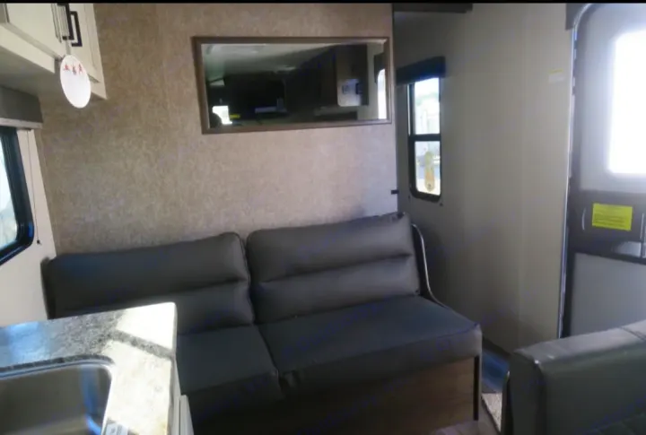 Spacious RV rental interior featuring a comfy gray sofa, large mirror, and kitchen area, perfect for your adventure.. Open Range Open Range 2021