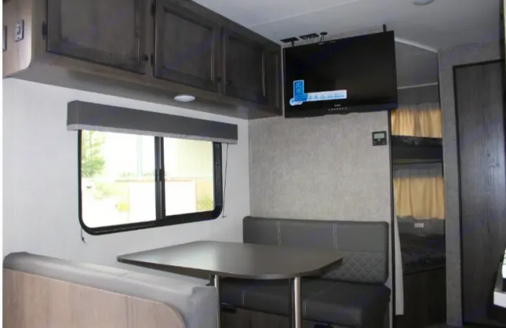 Comfortable RV rental interior: modern dinette, overhead cabinets, wall-mounted TV, & bunk beds. Great for your travels!. Open Range Open Range 2021