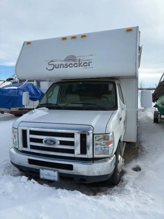 White Ford Sunseeker Class C RV rental with an over-cab sleeping area, parked in snow.. Forest River Sunseeker 2008