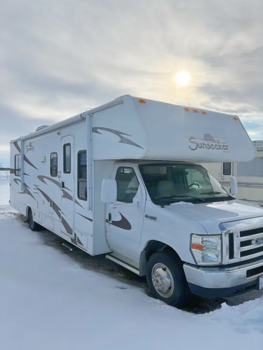 White Sunseeker RV rental, a Class C motorhome, parked in snow under a bright, cloudy sky.. Forest River Sunseeker 2008