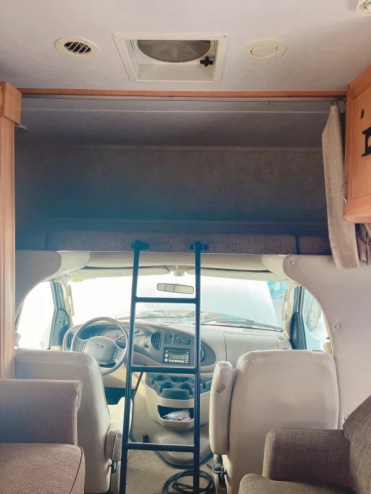 Inside an RV rental: view from rear to front, showing the cab, a ladder to the overhead bunk, and passenger seats.. Forest River Sunseeker 2008