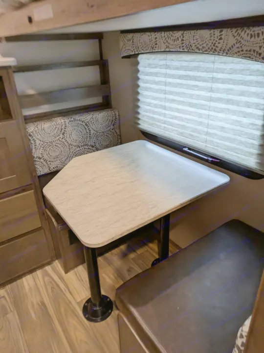 Cozy RV rental dinette featuring a light-colored table, patterned bench, brown bench, and a window with cellular blinds.. Cruiser RV MPG Ultra Lite 2019