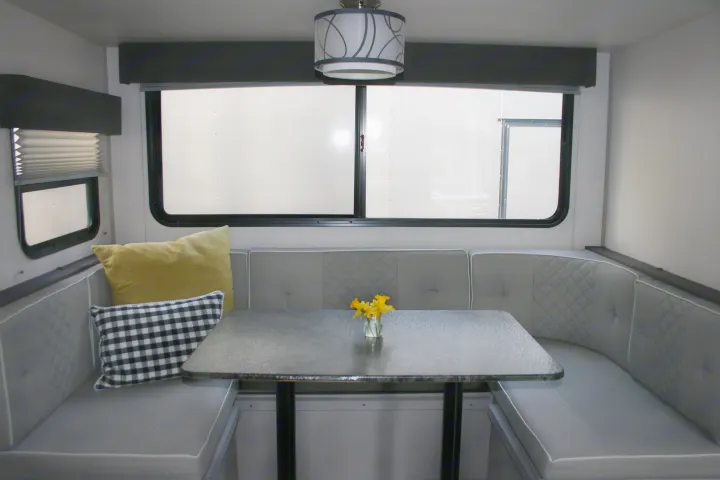 Comfortable RV rental dinette with U-shaped grey seating, table, and two windows for a cozy travel space.. Forest River Tracer 2022