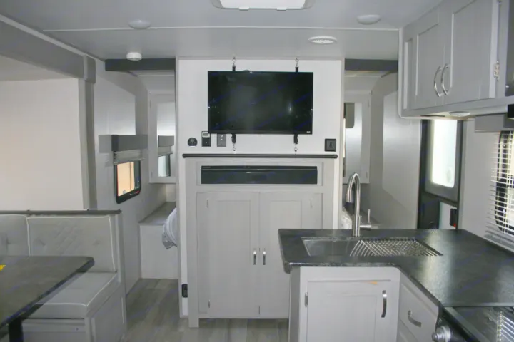 Explore this modern RV rental: a compact interior featuring a kitchen, dinette, entertainment TV, and glimpse of the bedroom.. Forest River Tracer 2022