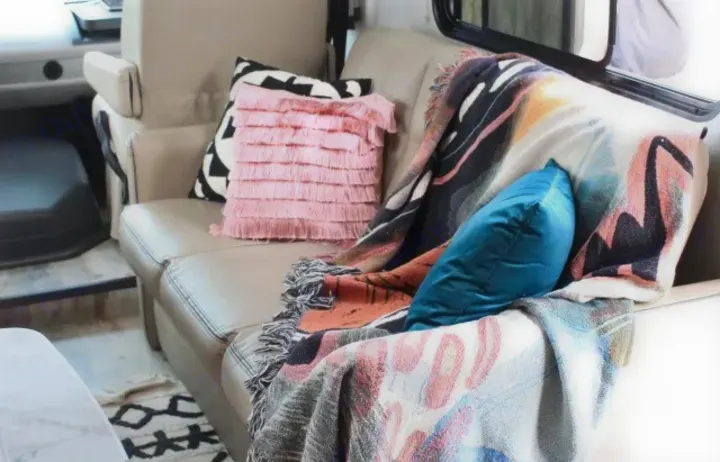 Cozy RV rental interior with comfy sofa, colorful pillows & blankets, perfect for relaxing on the road.. Coachmen Pursuit 2021