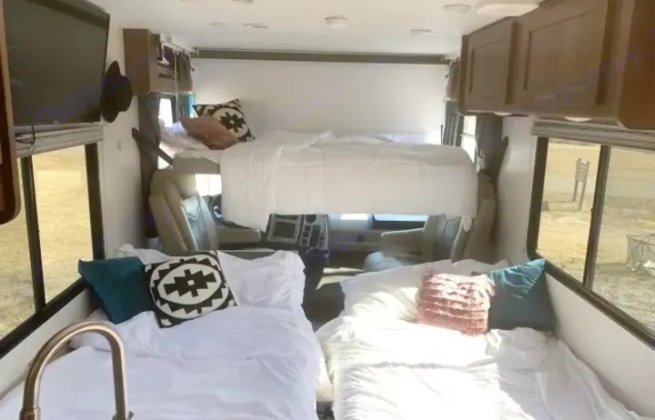 Bright rv rental interior featuring three comfortable beds, an overhead bunk, and kitchen area. Perfect for travel.. Coachmen Pursuit 2021