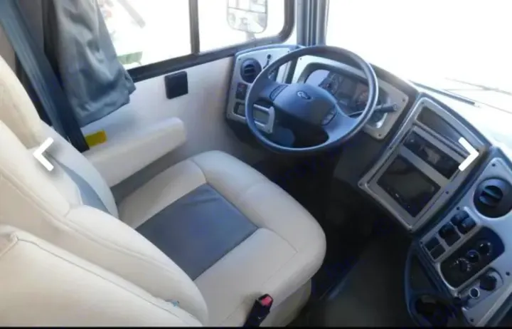 RV rental interior: view of the driver's seat, Ford steering wheel, and dashboard. Comfortable cream/gray seating.. Coachmen Pursuit 2021