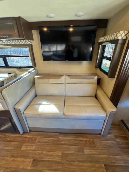 RV rental interior with comfortable light sofa, wall-mounted TV, and wood-look flooring. A welcoming living space.. Thor A.C.E. 2019