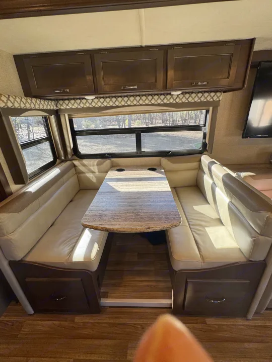 Comfortable RV rental dinette with benches, table, and large windows showing outdoors. Perfect for meals.. Thor A.C.E. 2019