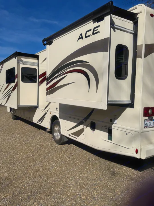 This A.C.E. motorhome, an ideal RV rental, shows its extended slide-outs parked on gravel under blue skies.. Thor A.C.E. 2019