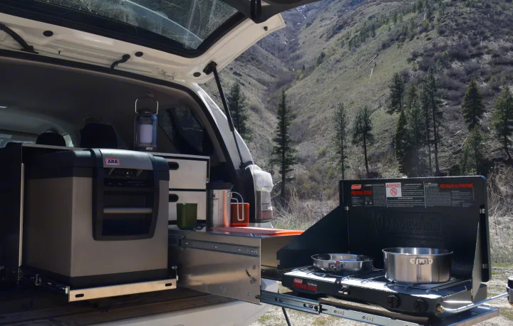 RV rental ready: vehicle's pull-out kitchen with ARB fridge, Coleman propane stove, and camping gear for outdoor cooking.. Toyota 4Runner 2021