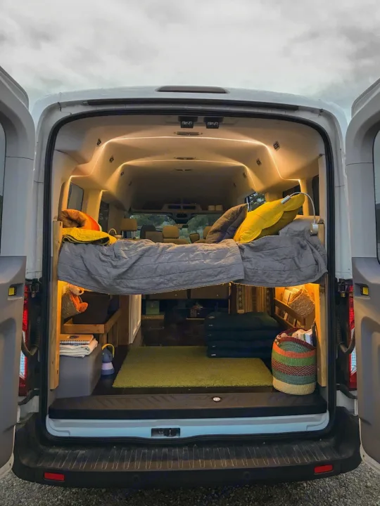 Cozy RV rental interior: a converted van with a bed, warm lights, and storage, perfect for mobile adventures.. Ford Transit Custom 2015