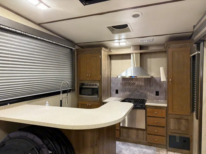 RV rental kitchen: modern, functional space with stove, microwave, sink, and storage cabinets for comfortable travel.. Keystone Sprinter 2018